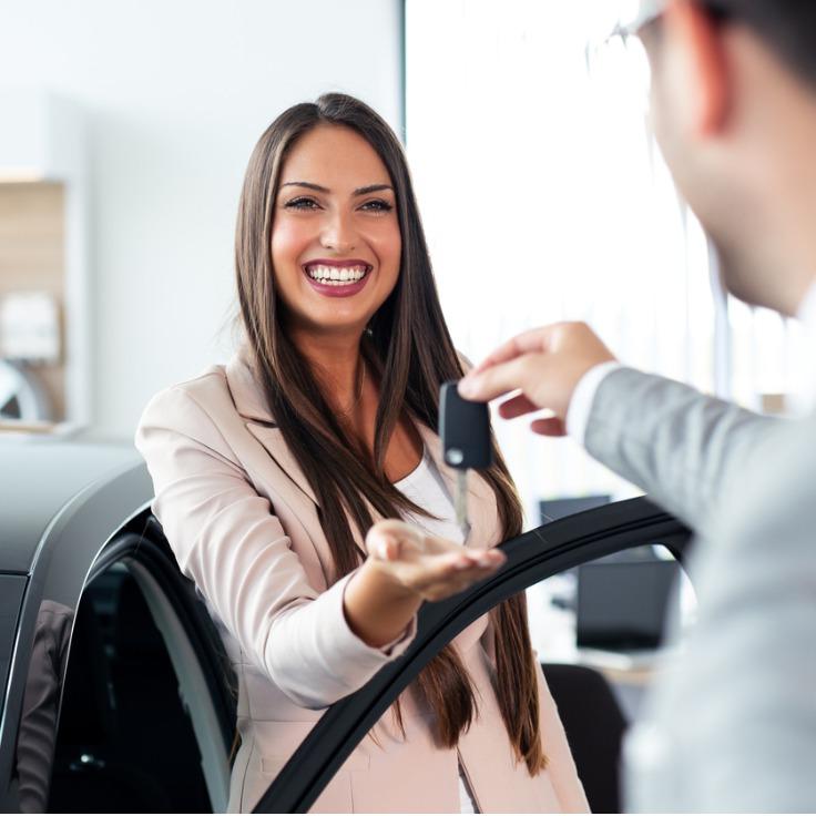 smiling car salesman handing over your new car keys happy girl the picture